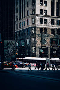 行人匆匆穿过光影斑驳的街角