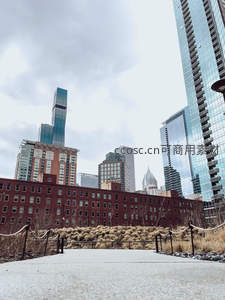 现代都市高楼林立，红砖建筑前小径蜿蜒