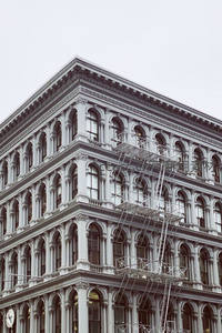 古典建筑转角立面，拱窗与铁艺消防梯交织光影