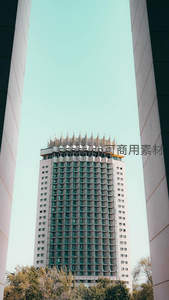 现代高楼耸立于两栋建筑之间，天空湛蓝