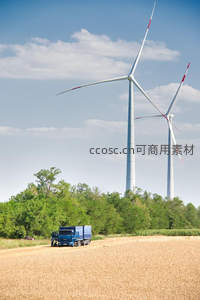 金黄麦田中的蓝色卡车与风力发电机