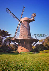 古典砖砌风车矗立在绿茵草坪上