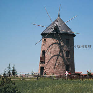 石砌风车矗立在青翠草地上