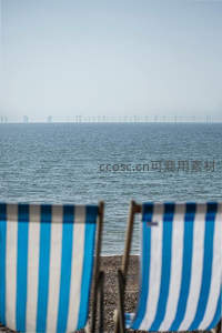 海边条纹躺椅与远处风力发电机