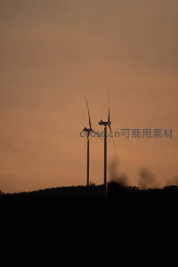 双风车剪影矗立山巅沐浴橙红霞光