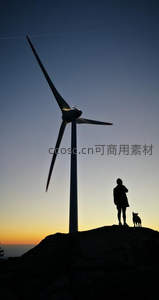 人与犬剪影伴风车共赏黄昏美景