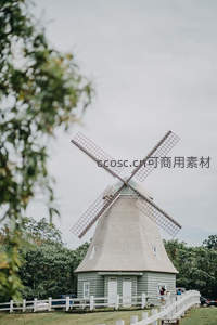 田园风车与绿树白栅栏的宁静风景