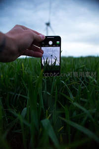 手机镜头捕捉风车，绿野中记录科技与自然