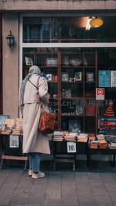 街头女子驻足橱窗前，凝视琳琅满目的书籍与小物