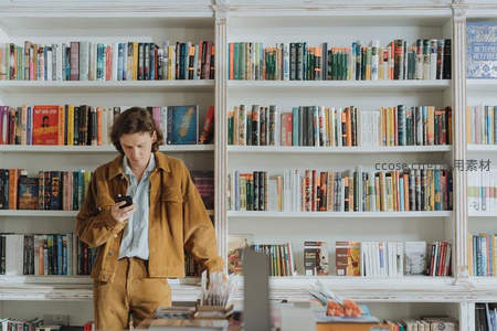 书店中低头看手机的年轻男子
