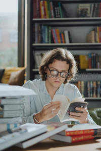 戴眼镜的年轻人在书房专注阅读书籍