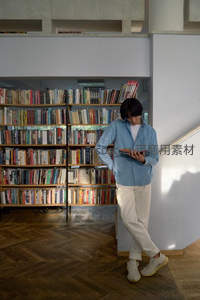 青年倚墙于图书馆阶梯旁读书