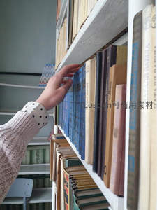 手轻抚书脊在图书馆寻找心仪读物