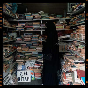 黑衣女子在堆满旧书的狭窄书架间挑选书籍