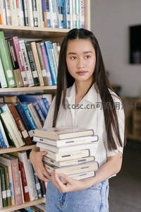 少女怀抱书堆在图书馆温柔凝视