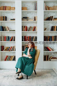 绿裙女子倚椅休憩，书海环绕静谧时光