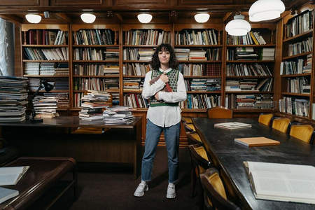 年轻学子怀抱书籍立于书架前