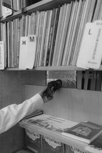 黑白光影中两人在书架前相握的手