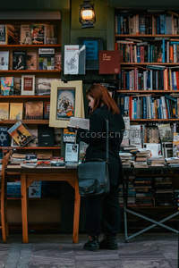 街头书摊前专注阅读的女子