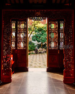 雕花红木门后映衬的古典园林