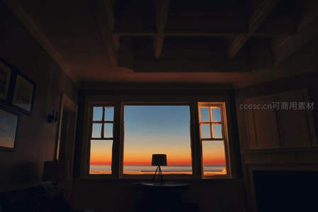 房间内窗框剪影映衬日落海景