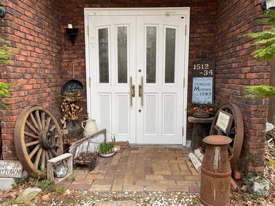 乡村民宿入口，白门配旧车轮与绿植装饰