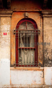 狮首雕饰窗楣下的红框铁窗