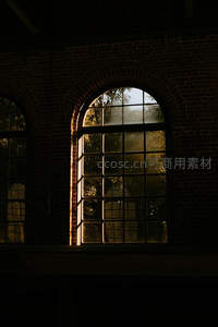 阳光穿透拱窗，照亮砖墙与树影