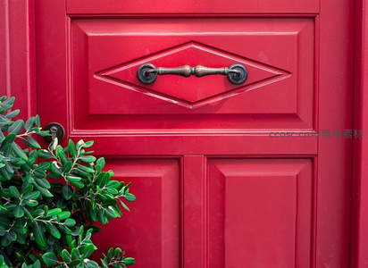 鲜红木门配铜环，绿叶点缀显生机