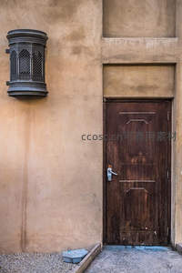 土黄色墙面老木门，复古壁灯相伴