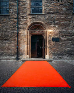 石砌教堂门前铺展鲜红地毯，庄重而神圣