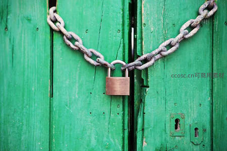 绿色木门上的铁链与铜锁特写