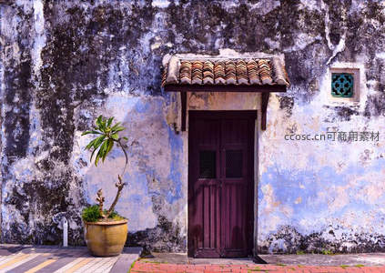 斑驳老墙前紫木门与盆栽