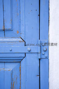 蓝色木门特写，岁月斑驳的纹理与金属铰链