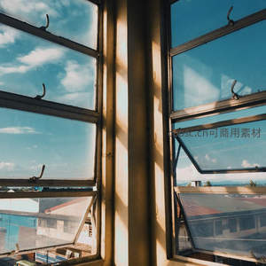 老式窗框透蓝天白云，阳光斜照城市屋顶