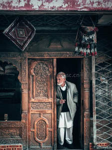 古朴雕花门前的沉思长者