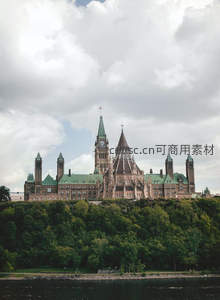 加拿大国会山建筑群屹立绿树丛中云影斑驳