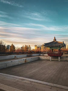 黄昏时分的传统韩式亭阁，现代都市天际线为背景
