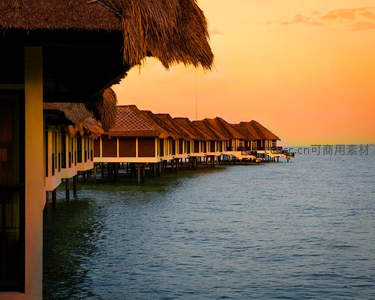 夕阳下的水上别墅，棕榈叶顶与海天一色