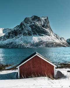 雪覆山峦旁的红色小屋静谧如画