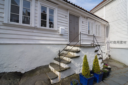 石阶通向白色木屋，蓝盆绿植点缀庭院