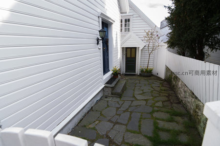 白色木屋旁的石板小径，绿草点缀其间