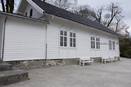 白色长屋前空地上的长椅与树木