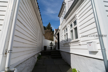 狭窄巷道里的白色木墙与蓝天