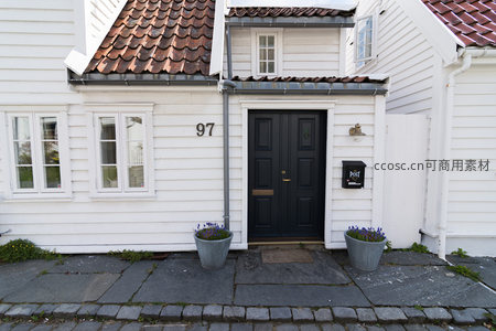 白色木屋门前黑门与紫花盆栽