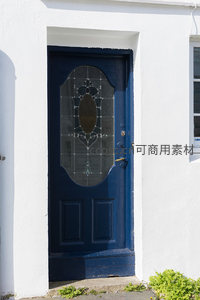 深蓝雕花门嵌于洁白墙面，光影交错显静谧