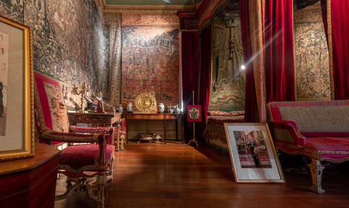 红丝绒帷幔环绕的帝王寝宫，挂毯与古董陈设典雅庄重