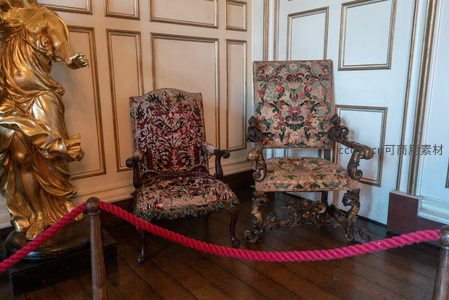 两把精雕细琢的古典扶手椅，陈列于金色雕像旁