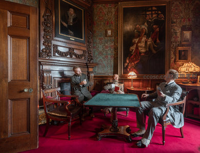 三位绅士在古典书房内围桌品茗交谈