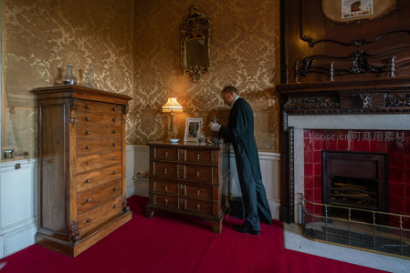 复古客厅中绅士整理古董柜的优雅瞬间